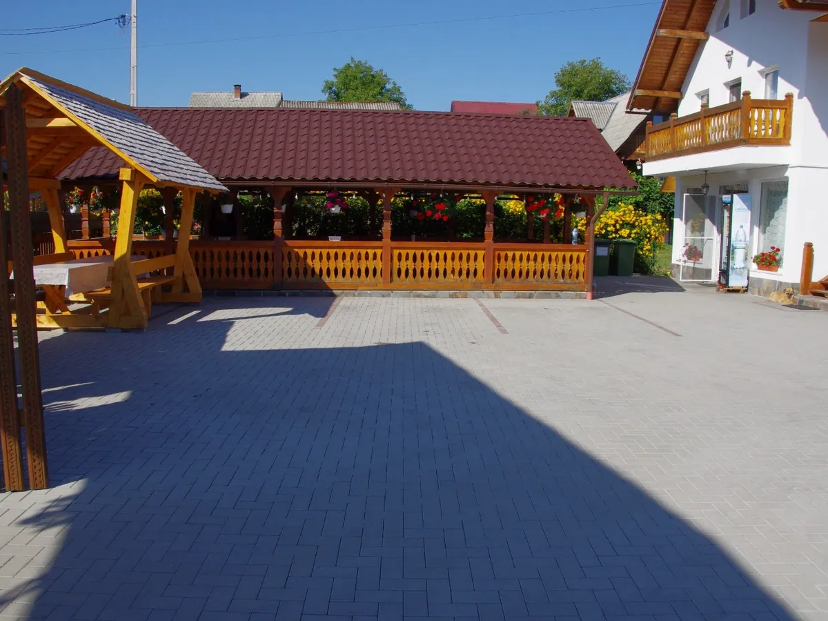 La cour de la maison avec son pavillon en bois et les bâtiments aux toits rouges