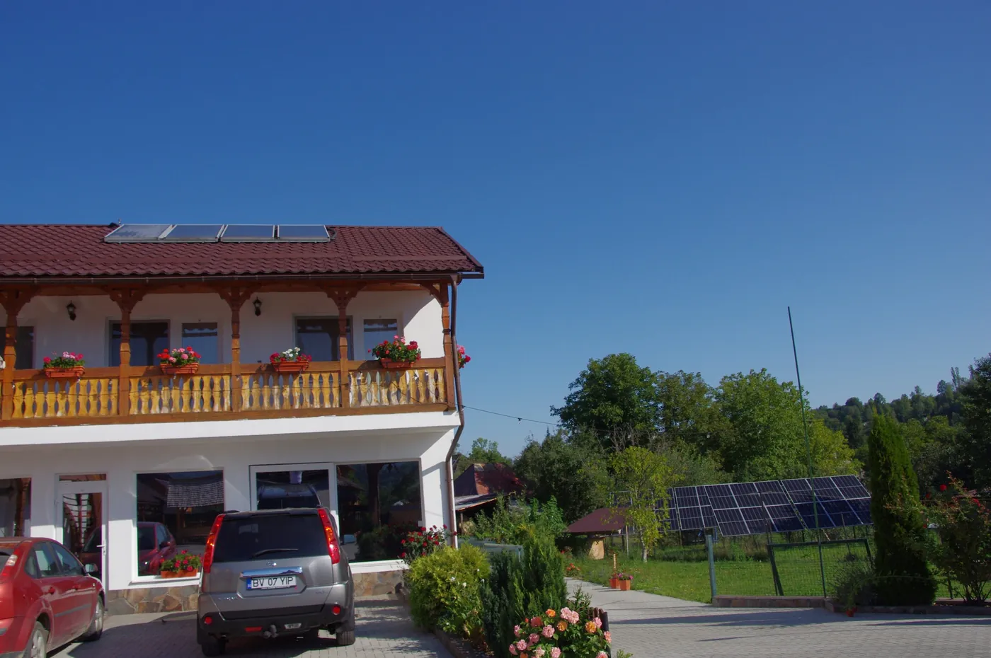 Fațada pensiunii, cu balcoane de lemn și acoperiș roșu
