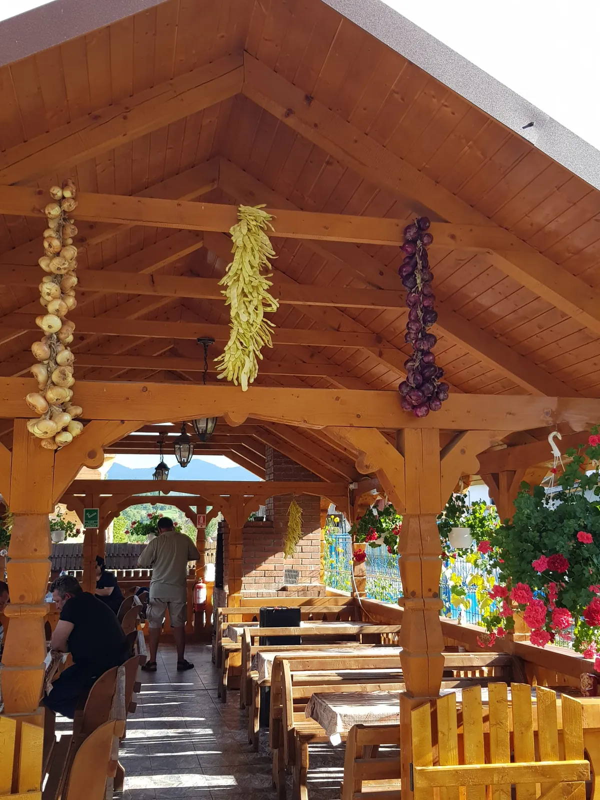 Interiorul foișorului de lemn, cu ciorchini de ceapă și porumb atârnați