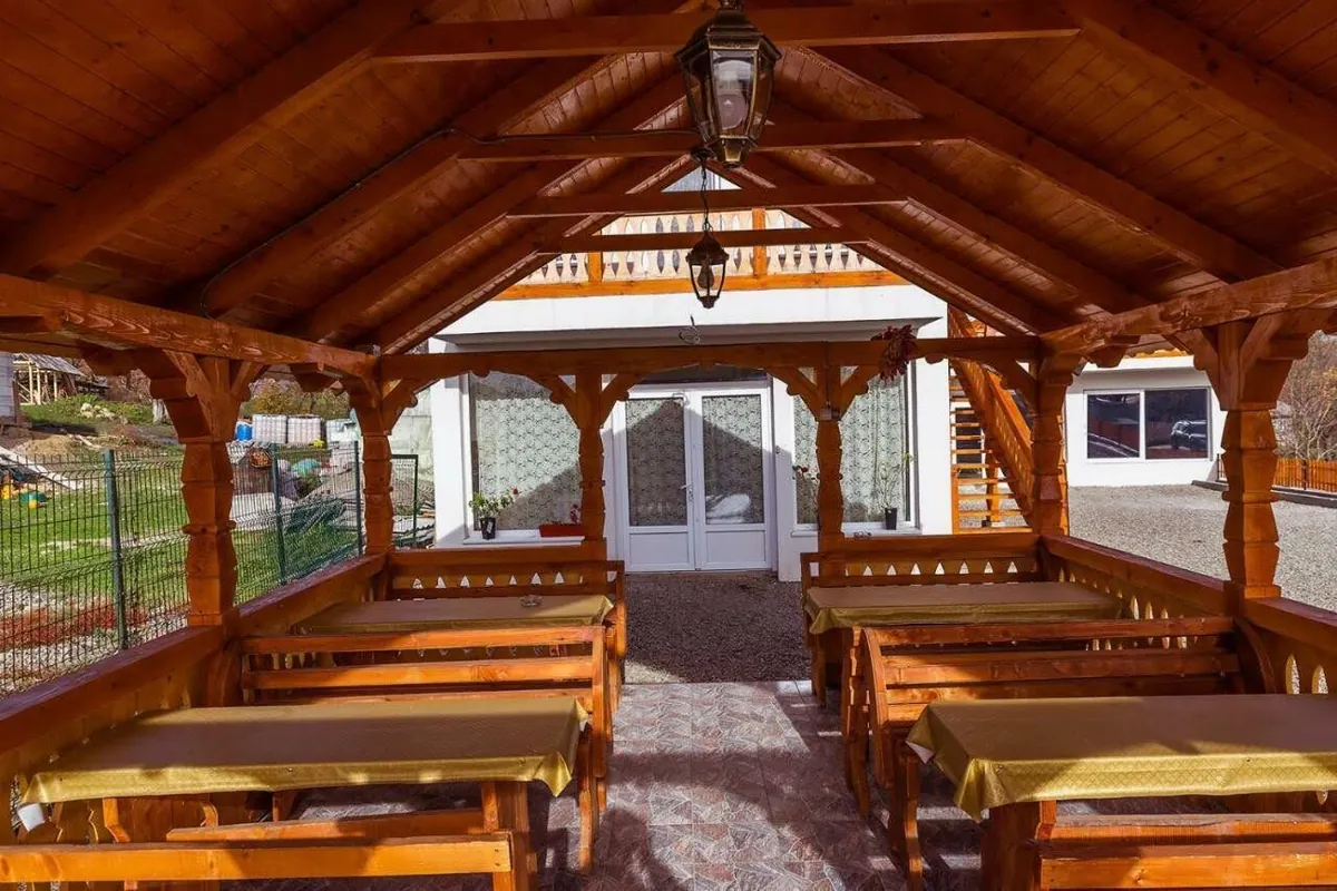 Interior din lemn cu mese lungi, pregătit pentru oaspeți